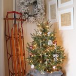 Christmas entryway with copper boiler tree stand, vintage sled, and framed vintage Christmas sheet music.