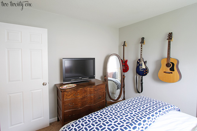 Bedroom painted with Repose Grey. Vintage dresser with a TV on top. Three guitars handing on the wall.