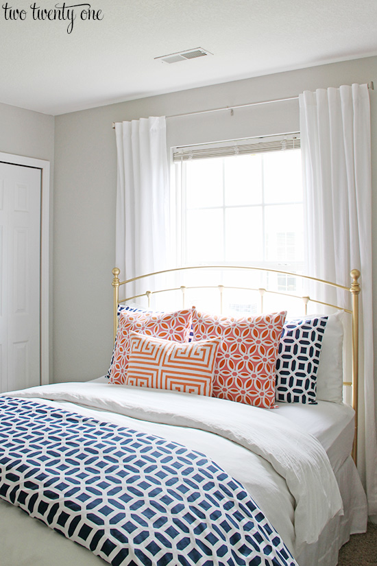 Navy and coral bedding with Sherwin Williams repose gray walls.