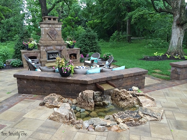 outdoor fireplace and sitting area with water feature