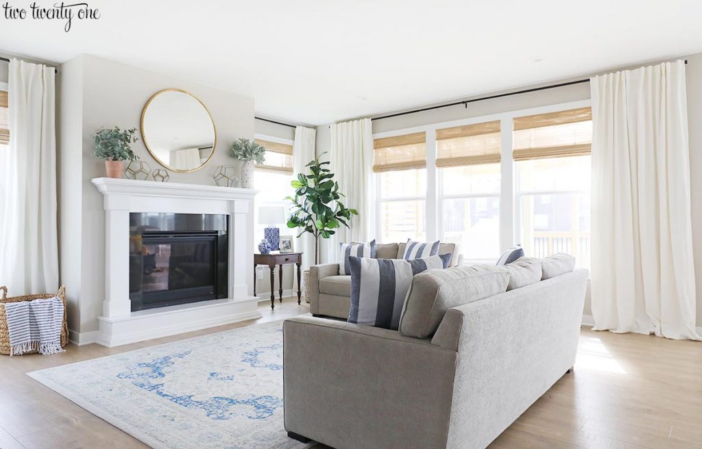 living room with white curtains and woven shades