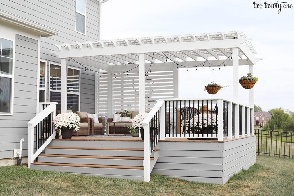 White pergola with white privacy screen on top of a deck withe gray stained horizontal deck skirting