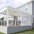White pergola with white privacy screen on top of a deck withe gray stained horizontal deck skirting