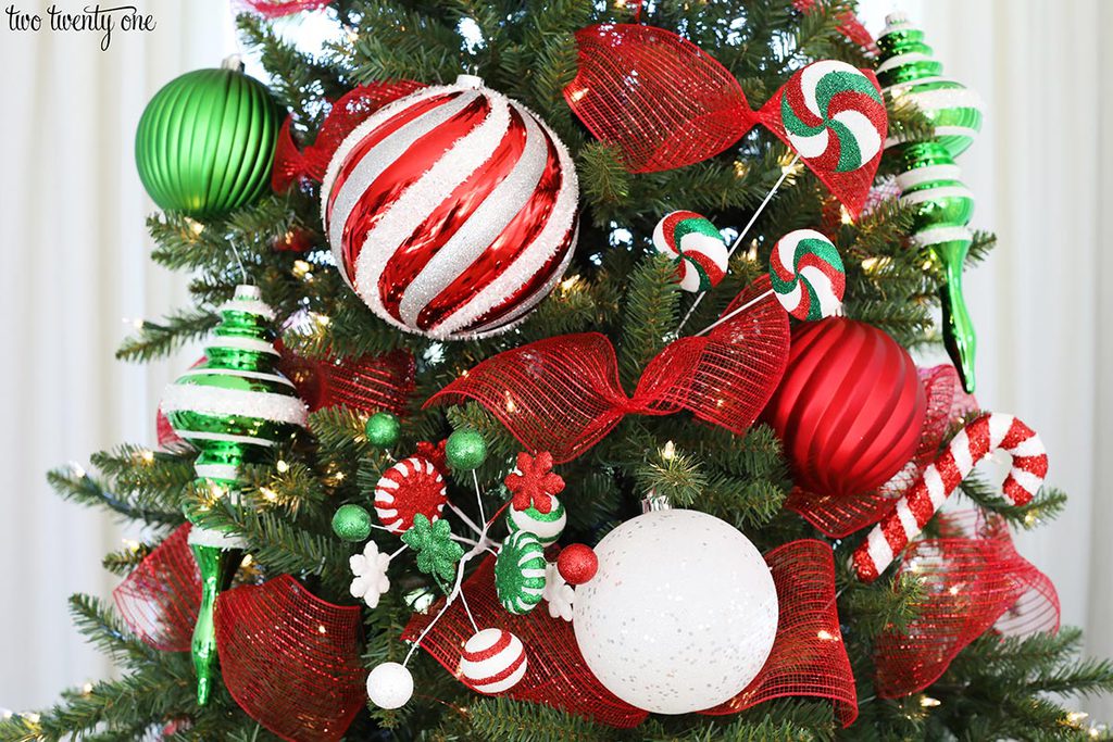 artificial christmas tree with red white and green ornaments, red mesh ribbon and red, white and green picks