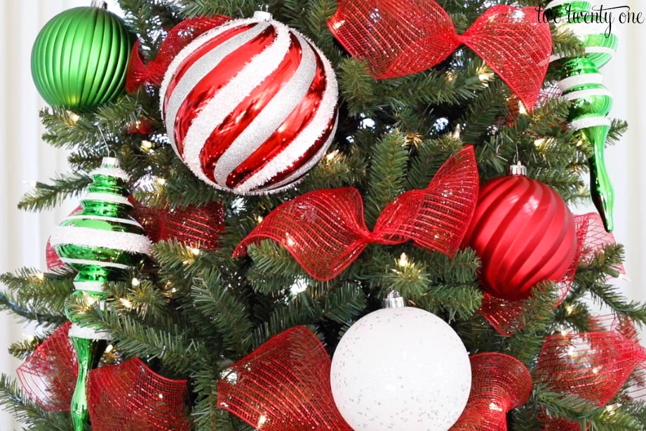 different size red white and green ornaments with red mesh ribbon