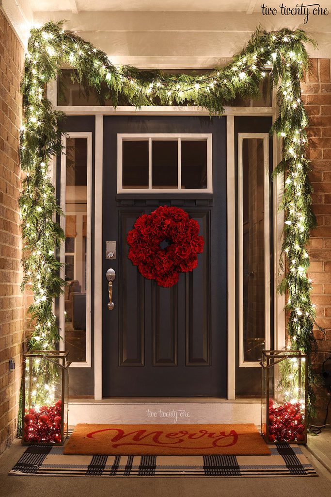 front door decorated for Christmas with cedar garland and lights