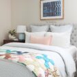 bed with vintage quilt, blue and white striped duvet, blue striped euro shams, white pillows, and light pink pillow. Shibori wall art above the bed.