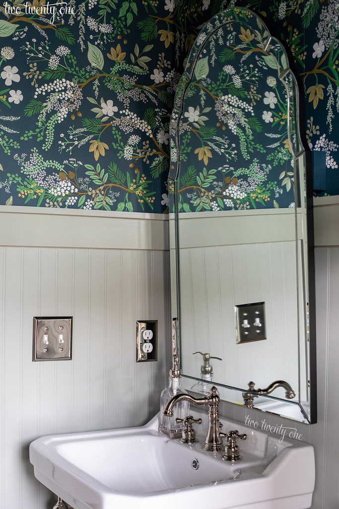 victoriahaus console sink with kingston brass american classic faucet, and uttermost brayden vanity mirror. rifle paper co juniper forest wallpaper and benjamin moore oil cloth paint on the walls