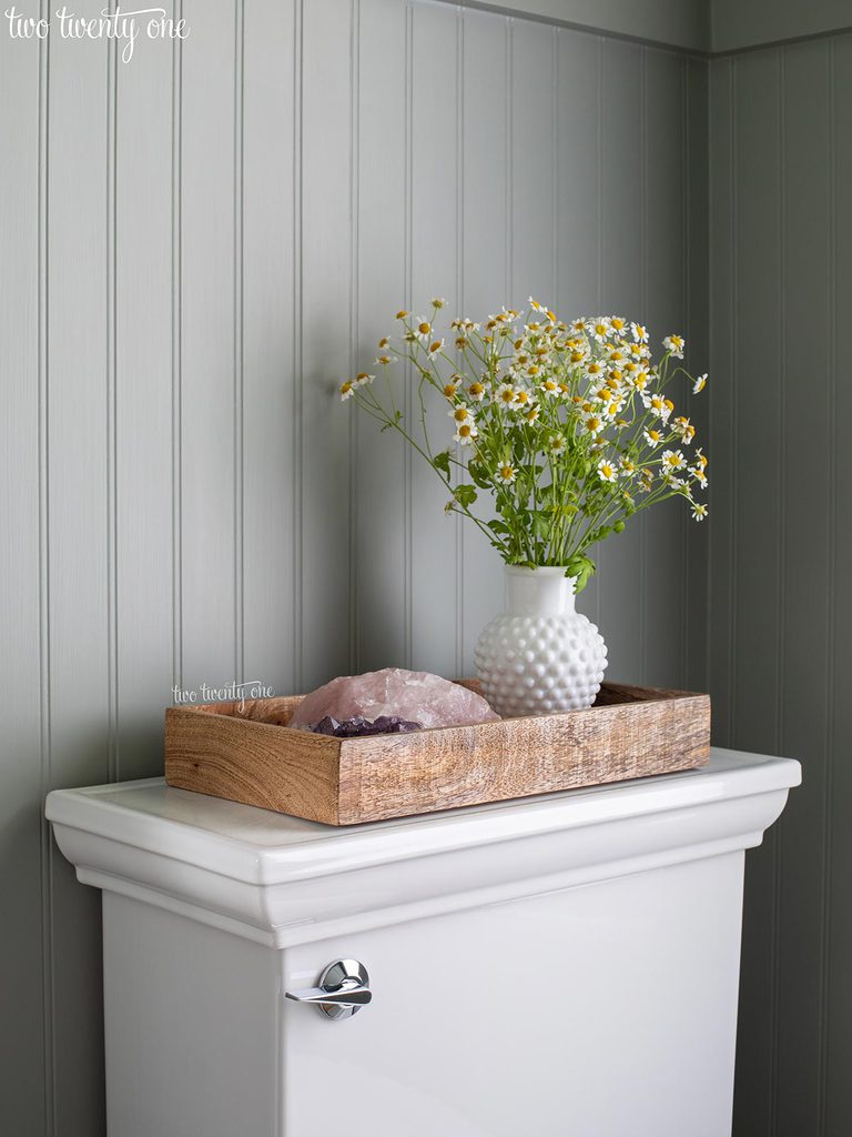 kohler memoirs toilet with wooden tray on top with chamomile flowers in white hobnail vase