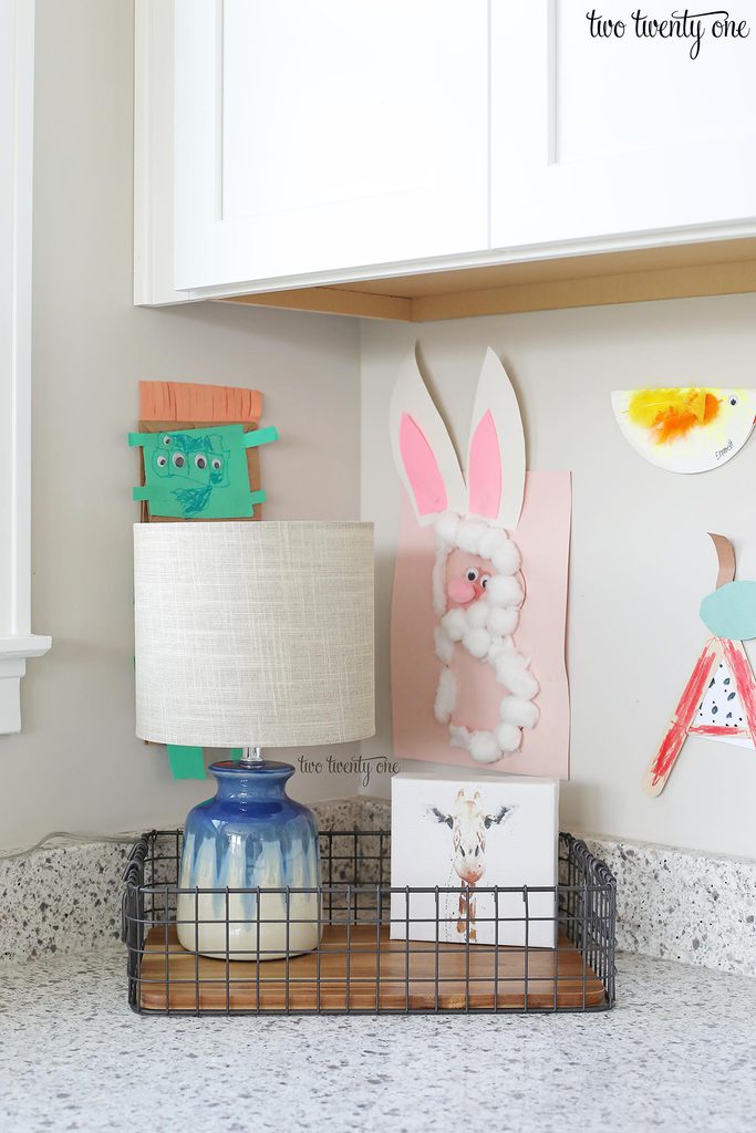 A small lamp and giraffe print inside a wood and wire tray.