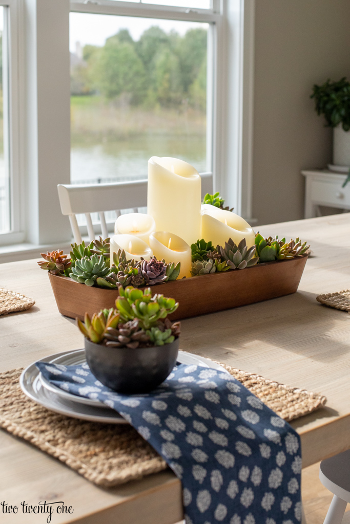 Place setting layered with dinner plate, salad plate, napkin, and succulent planter.