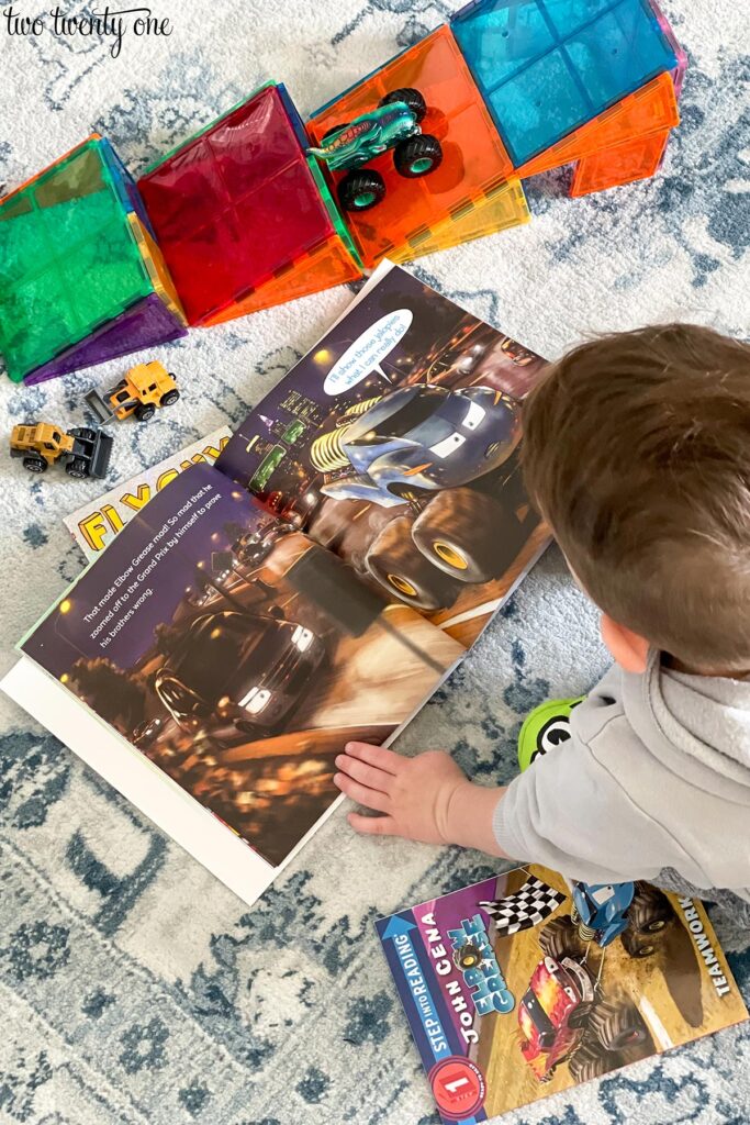 child looking at a book about monster trucks