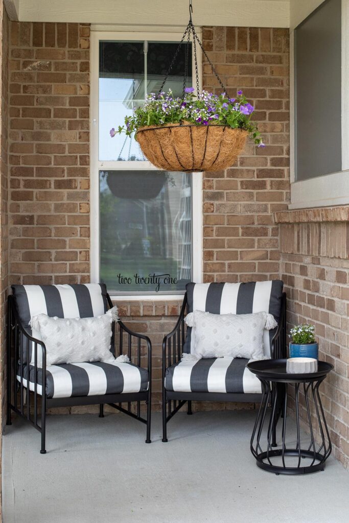 front porch with black and white patio furniture chairs and side table