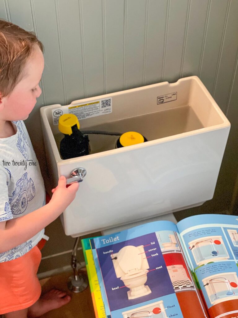 little boy looking at inside of toilet tank