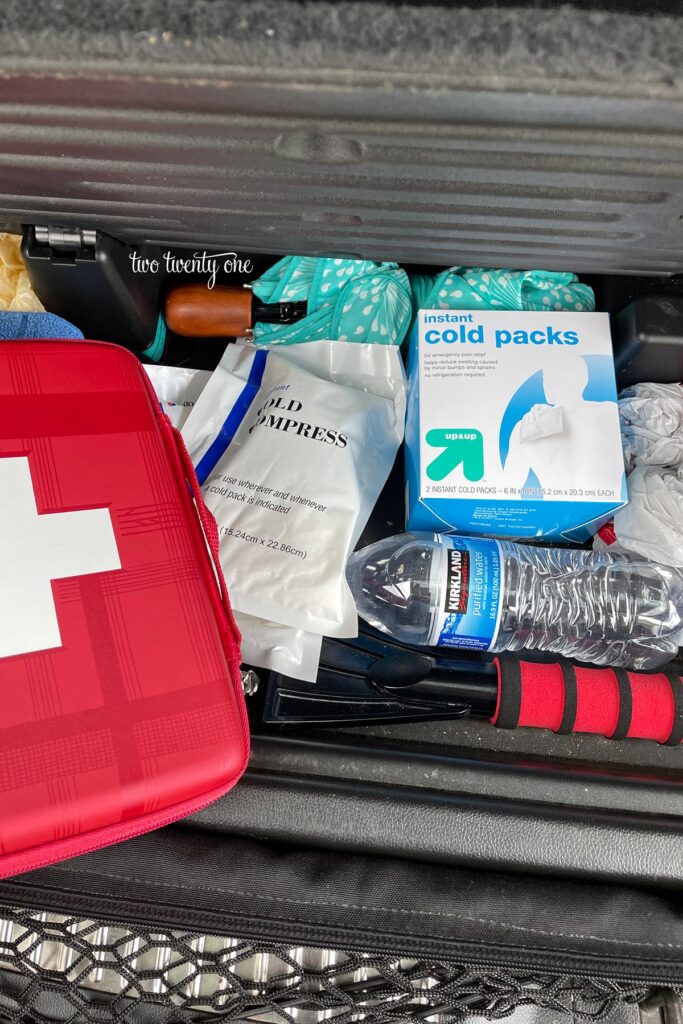 car organization hacks - trunk compartment with first aid kit, cold compresses, bottle of water