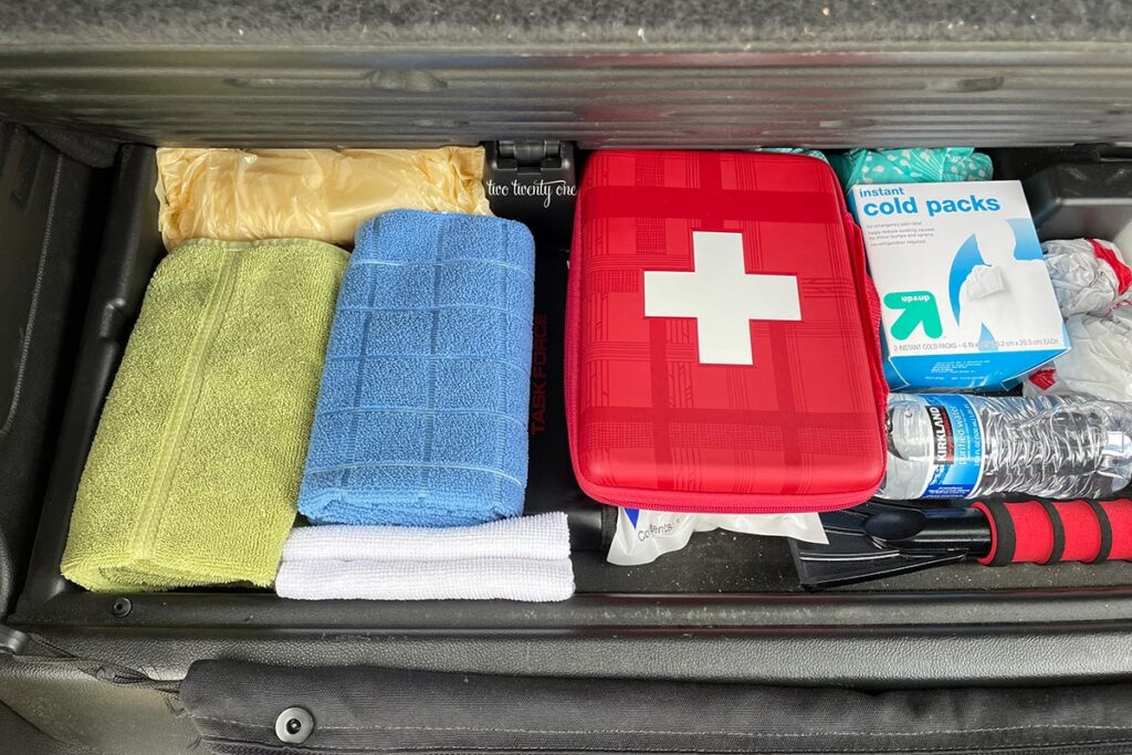 car organization hacks - hidden car trunk compartment with towels, first aid kit, cold compresses