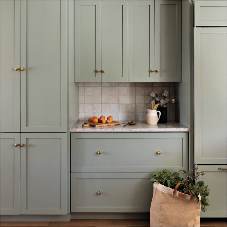 Kitchen cabinets painted with Benjamin Moore Oil Cloth, a muted green color. A tiled alcove is between a set of lower drawers and upper cabinets.