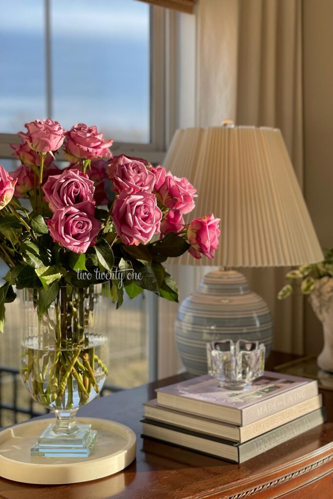 Purple roses from Costco in a clear glass vase on top of a dresser.