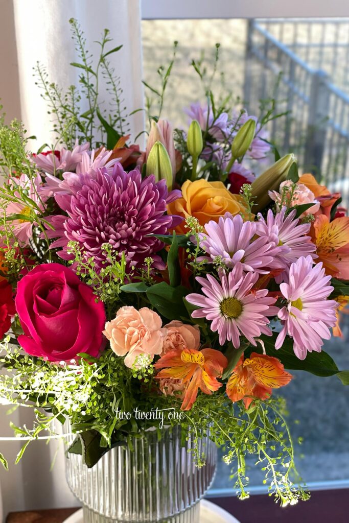 A mixed flower bouquet from Costco. Flowers include purple mums, pink roses, orange alstroemeria, and greenery.