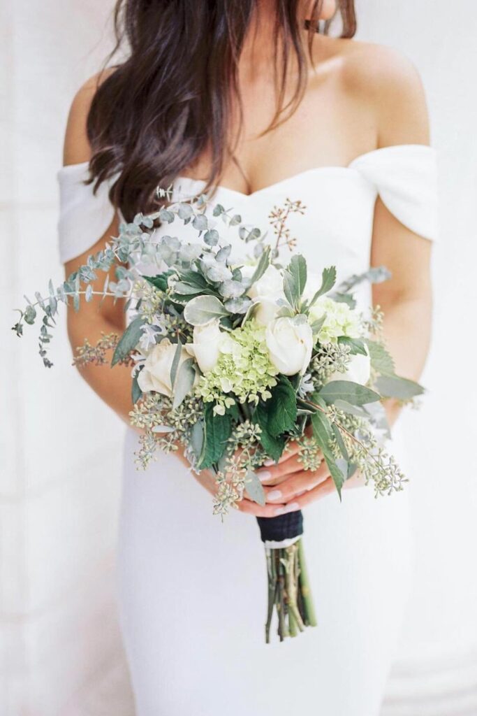 Wedding bouquet with various white flowers and greenery.