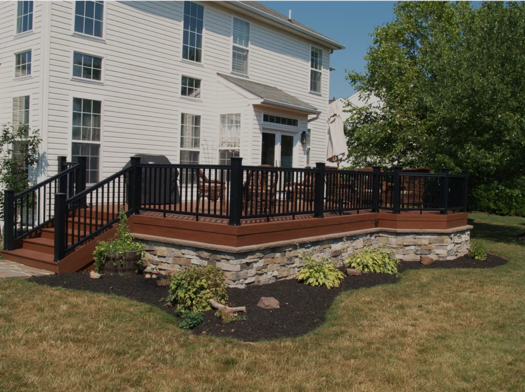 Wood deck with black railing and stone skirting